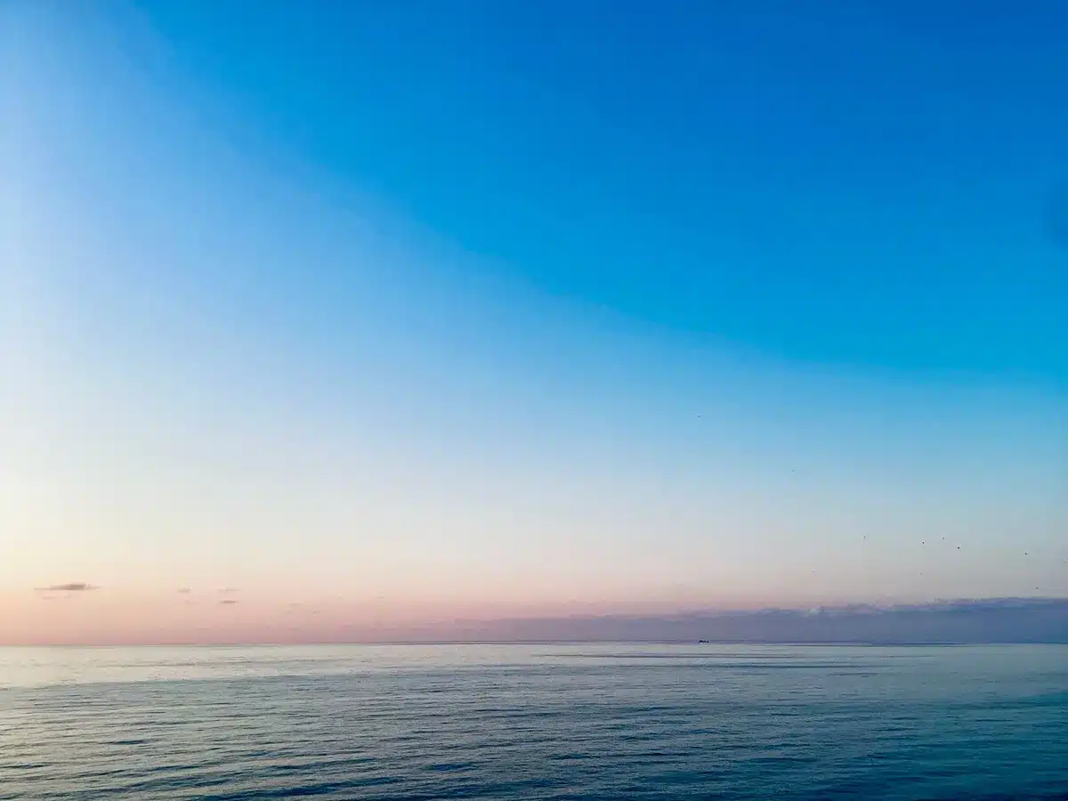 Il mare al sorgere del sole con luce dorata che riflette sulle onde