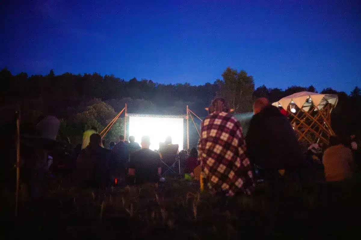 Pubblico seduto in una sala cinematografica durante una proiezione, con lo schermo illuminato sullo sfondo