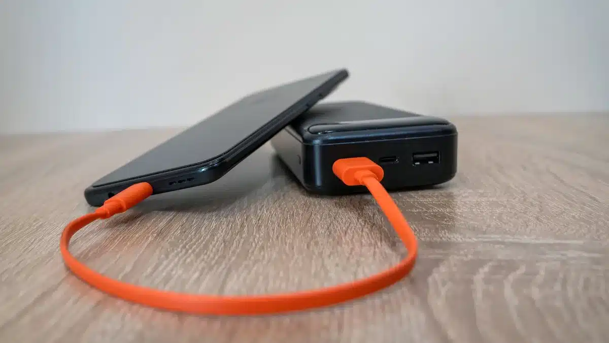 Smartphone in ricarica su una base wireless con power bank accanto