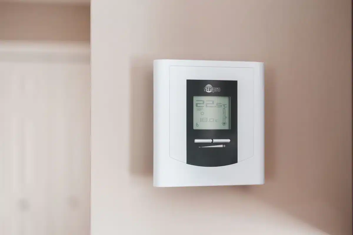 Mano che regola un termostato intelligente per ottimizzare i consumi energetici