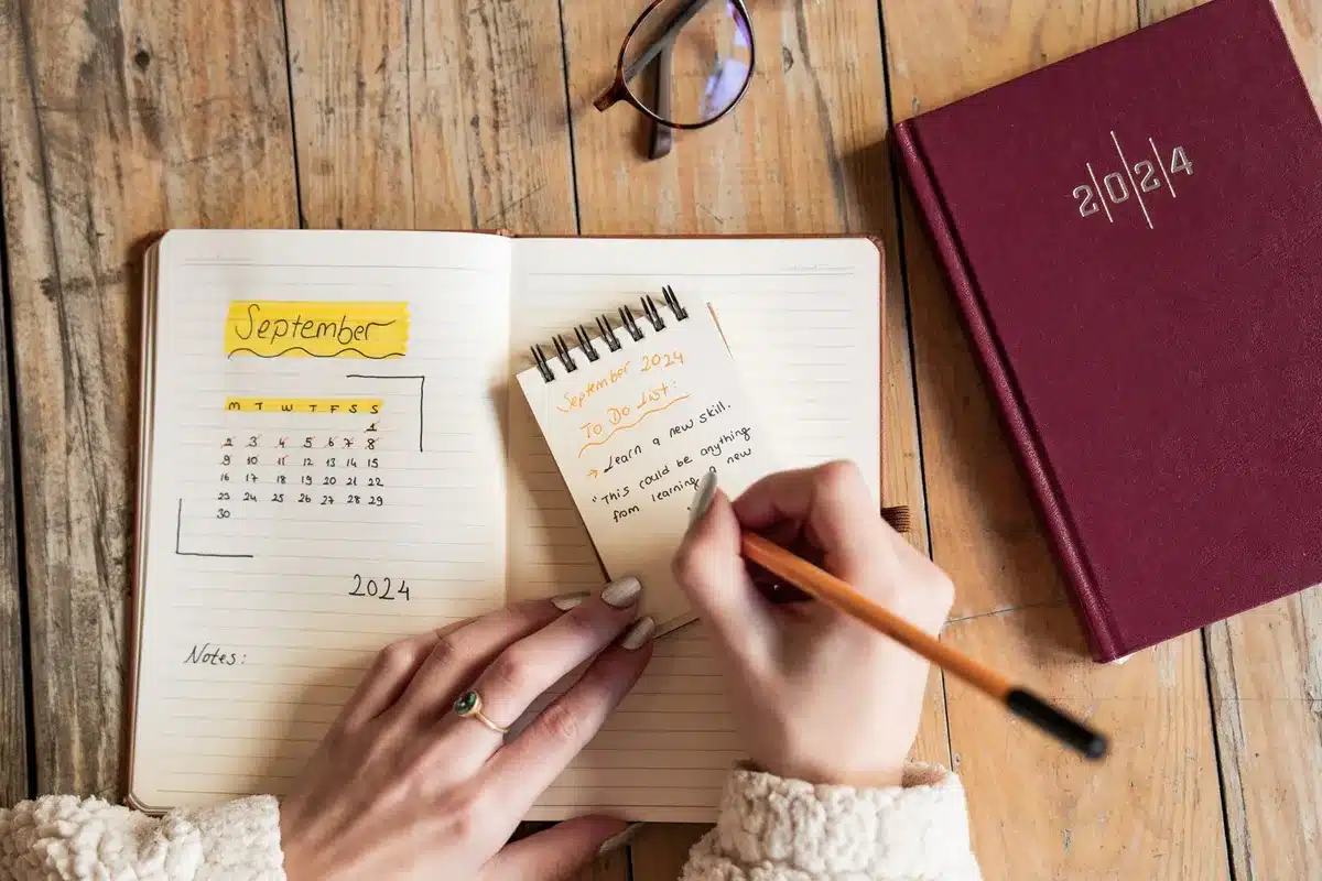 Persona che gestisce il tempo con app e planner cartaceo sulla scrivania