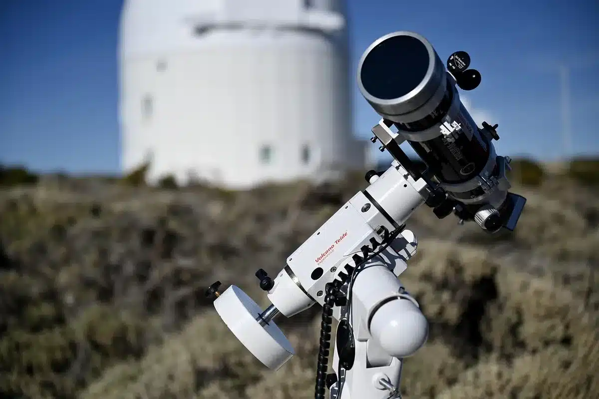 Persona che osserva il cielo notturno stellato con un telescopio in un'area buia