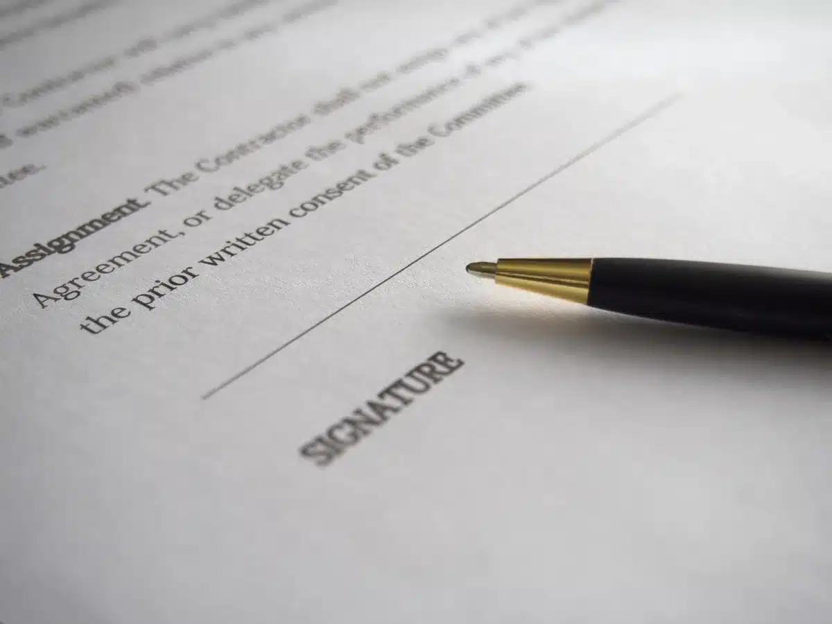Firma di un contratto commerciale internazionale su documenti in una sala riunioni professionale