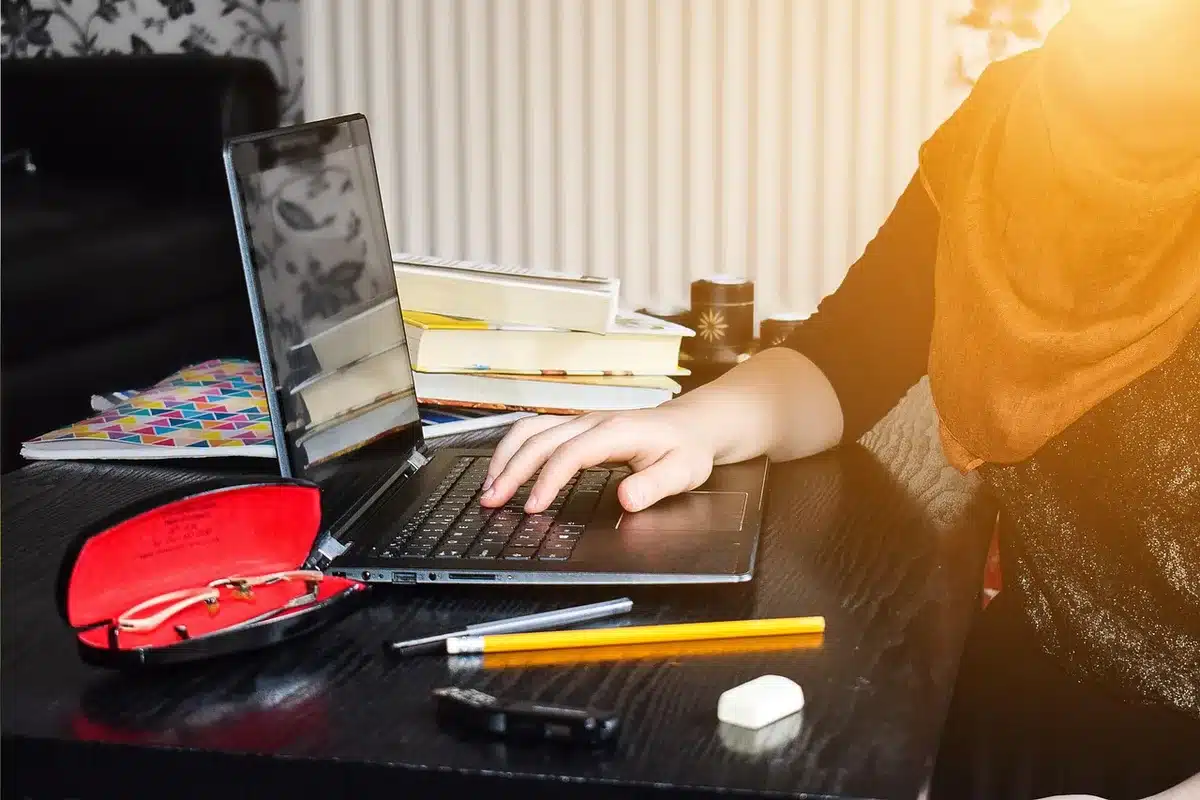 Persona che studia online al computer con libri e appunti sulla scrivania