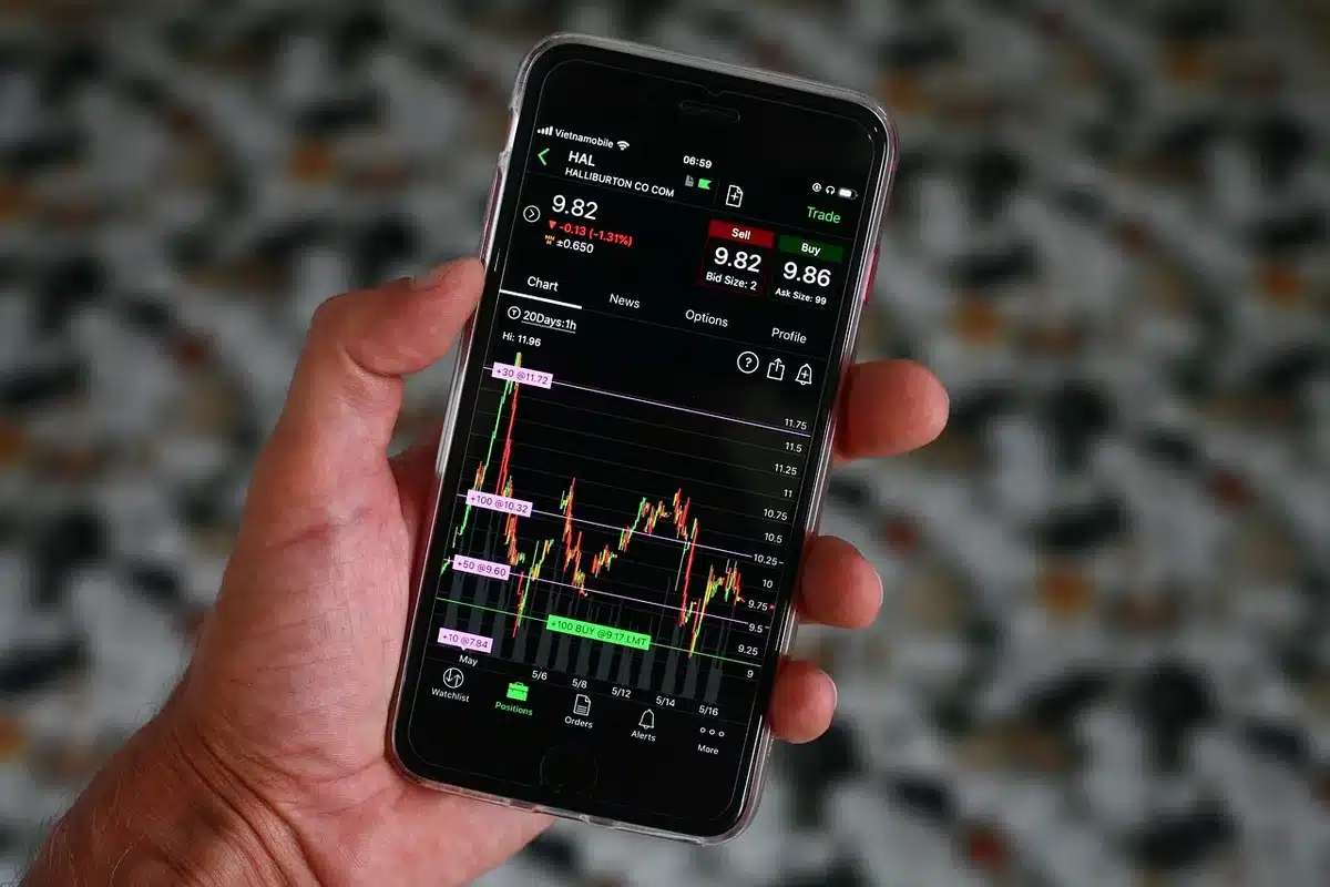 Sala di trading affollata con schermi che mostrano grafici rossi e verdi, simbolo della volatilità dei mercati finanziar