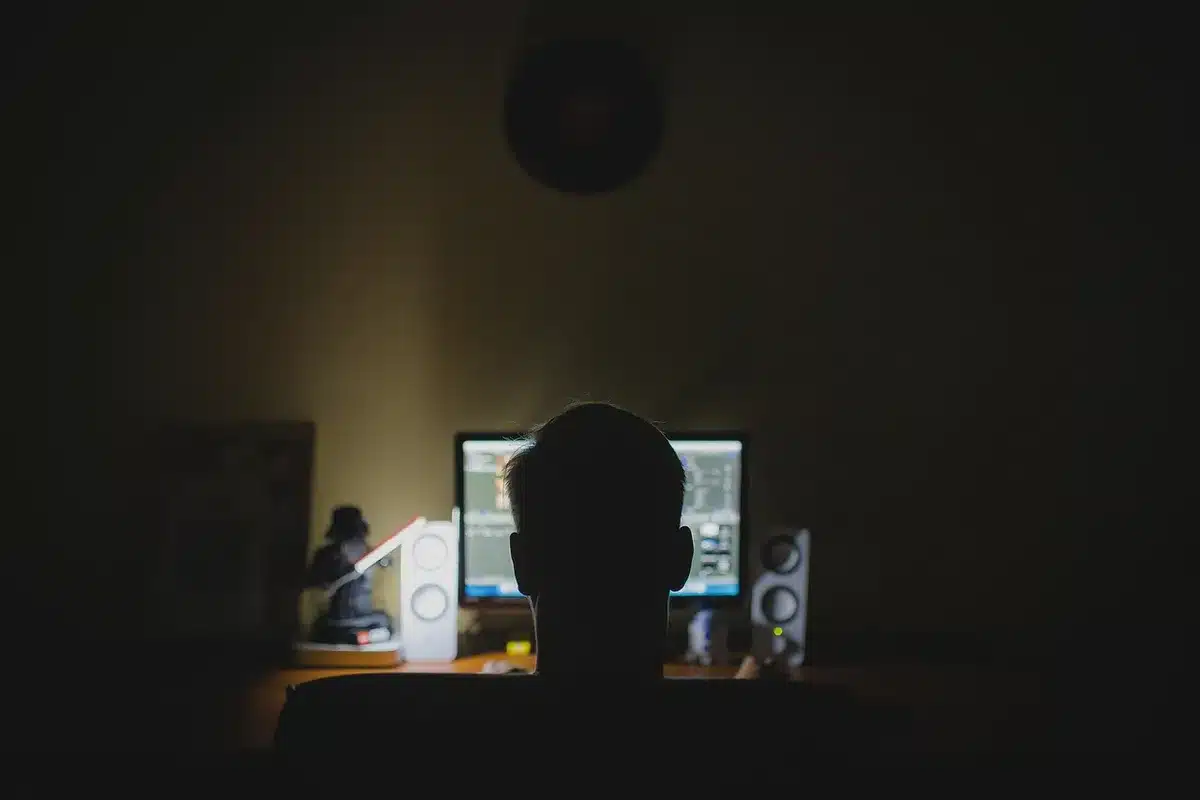 Corridoio d'uffici con scrivanie vuote e monitor spenti, figura sfocata sullo sfondo