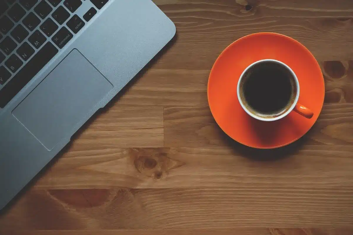Polso con smartwatch vicino a taccuino e caffè in un interno luminoso