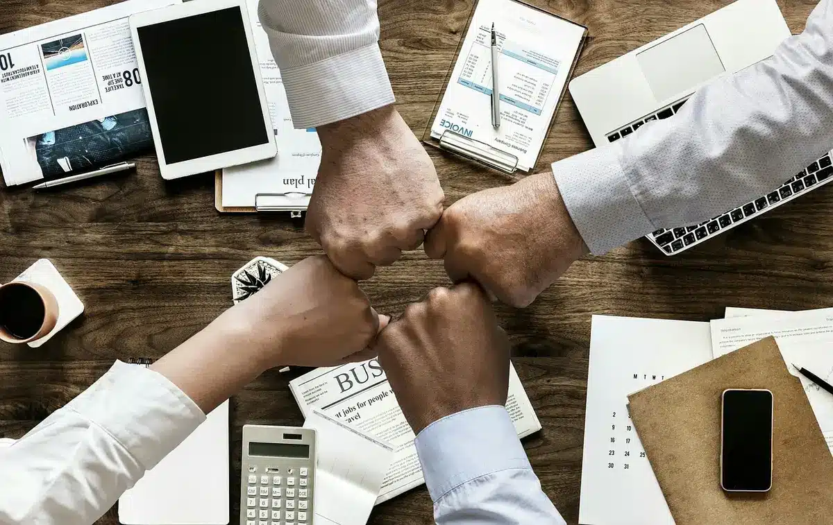 Mani che consultano documenti finanziari accanto a un laptop e una calcolatrice in ufficio