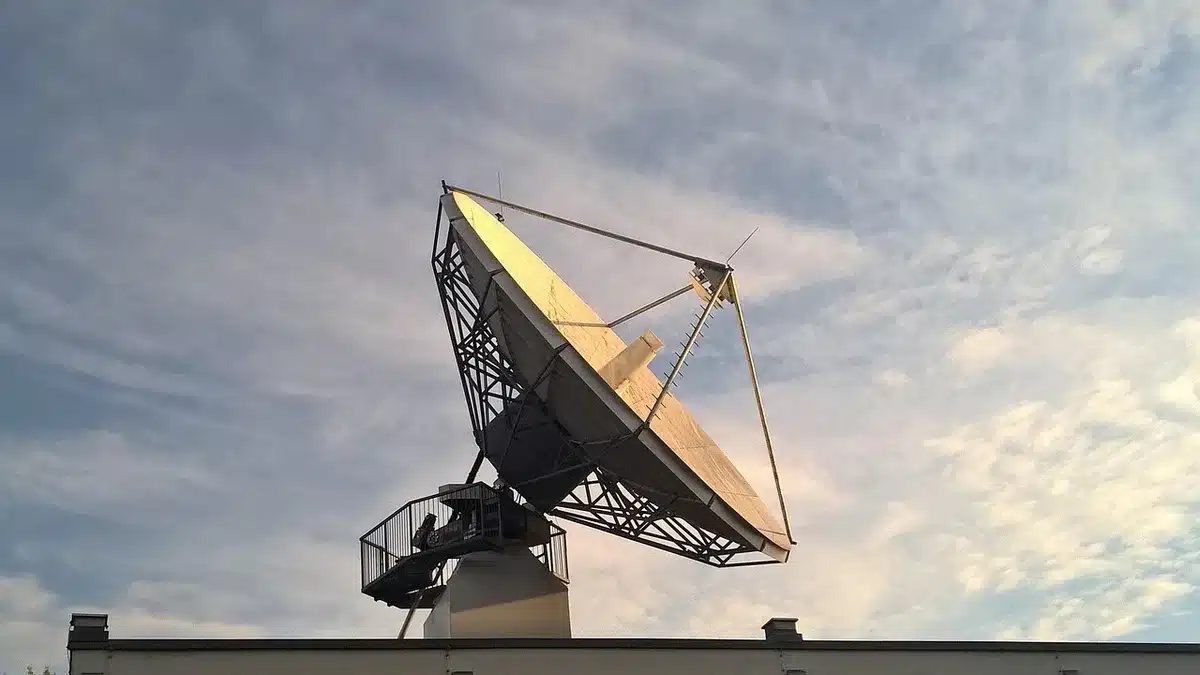 Tecnici anonimi in sala operativa con monitor di rete e antenna parabolica