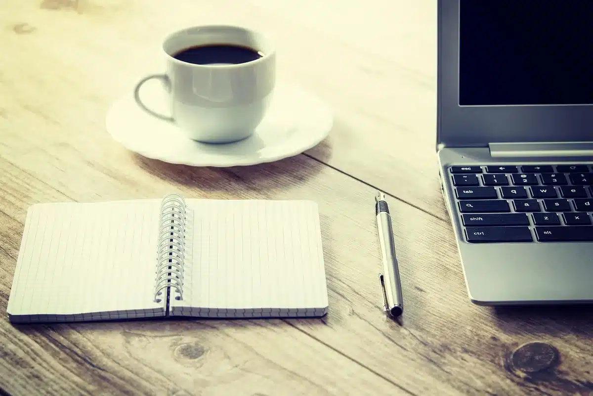 Scrivania di redazione con fogli di sondaggi e laptop, mano che indica un grafico